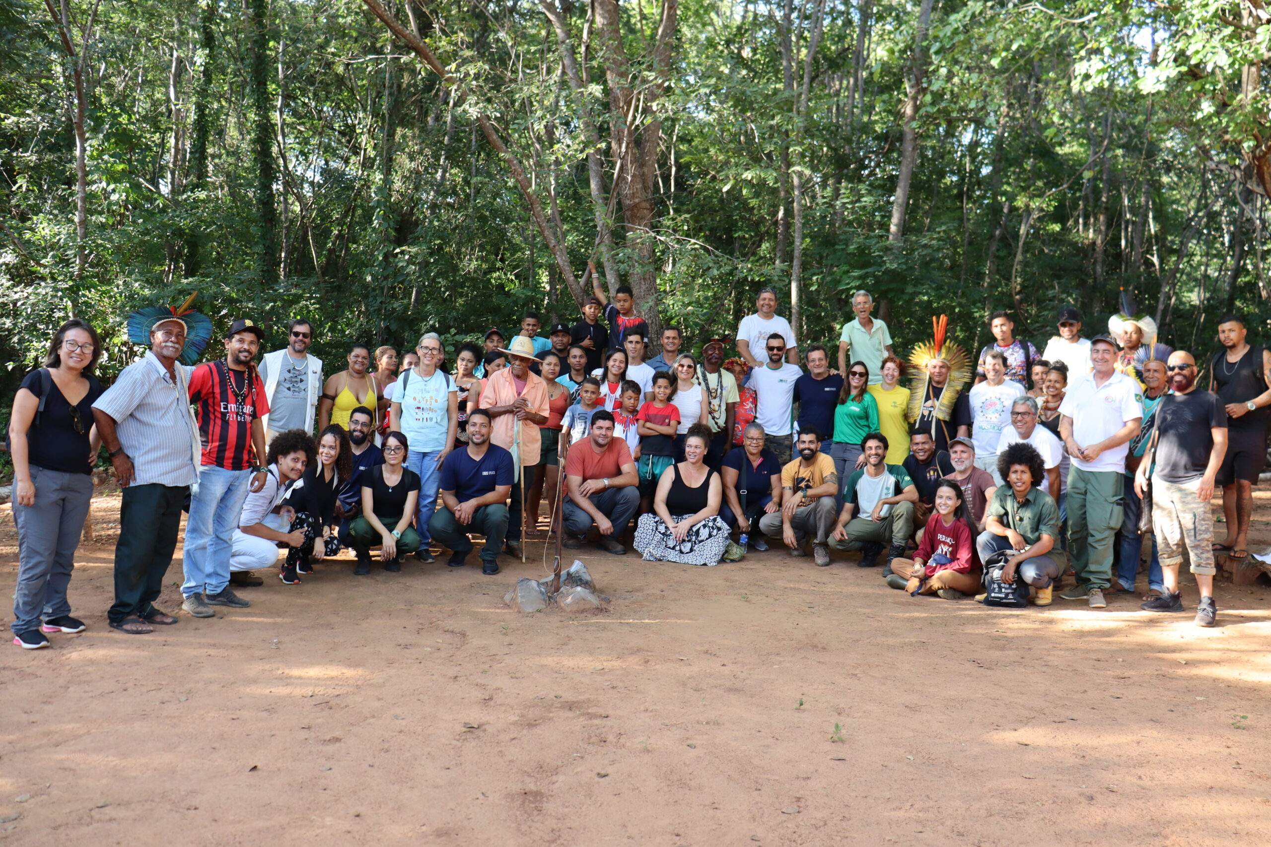 Acessibilidade e plantas medicinais pautam novos projetos no Mosaico Sertão Veredas Peruaçu. Na foto, está o grupo de participantes do momento, todos sorridentes e em frente a uma floresta verde de árvores altas e com chão de barro.